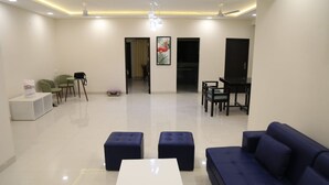 A modern living room with a sofa, ottomans, a coffee table, and a dining area with chairs and a table.