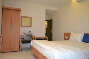 Un dormitorio con cama, armario, mesita de noche y espejo en la pared.