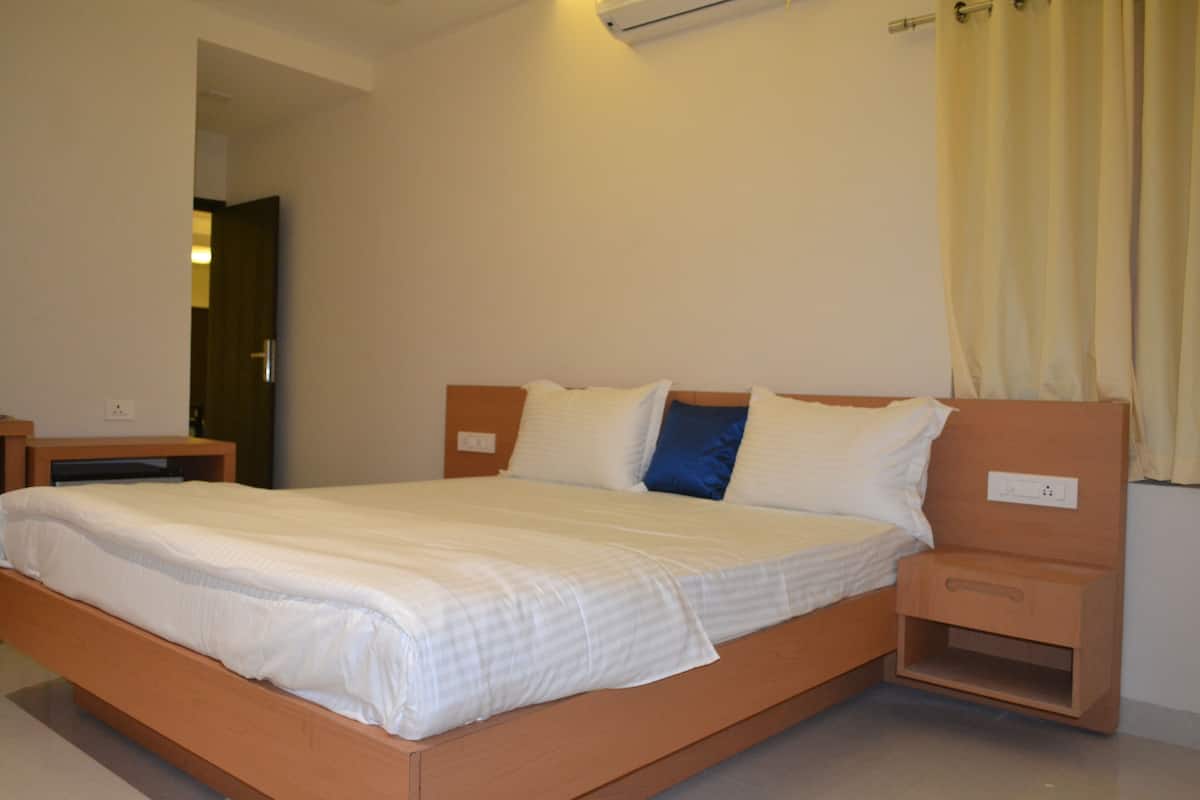 Una cama bien hecha con cabecera de madera, una mesita de noche y una mesilla.