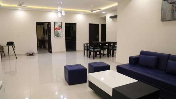 A modern living room with a sofa, ottomans, a coffee table, and a dining area with chairs and a table.
