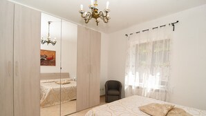 Un dormitorio con cama, una silla, un armario y una araña.