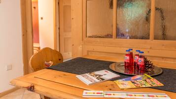 A wooden table with a black placemat, a pine cone, and red bottles.