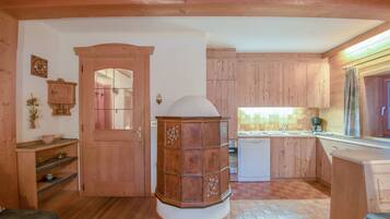 A wooden interior with a kitchen area, a central wooden cabinet, and a door leading to another room.