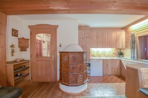 Un intérieur en bois comprenant un espace cuisine, un meuble central en bois et une porte donnant sur une autre pièce.