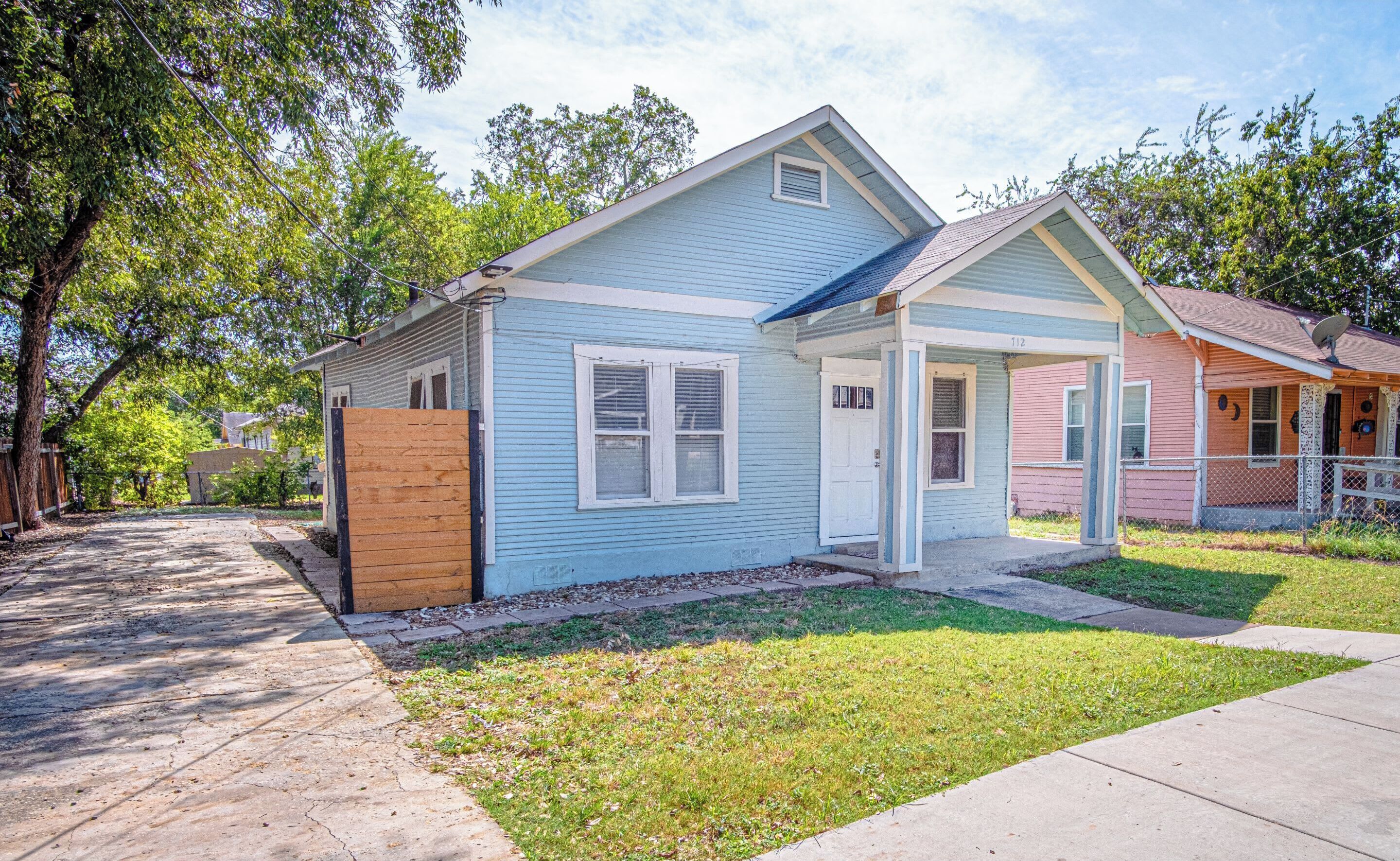 A two-story residential building with a blue exterior, a front porch, and a visible front door.