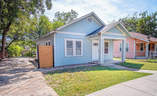 A two-story residential building with a blue exterior, a front porch, and a visible front door.