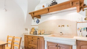 Una cocina con armarios de madera, encimera de mármol y una barra para colgar ollas.