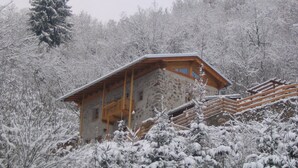 Un edificio de piedra con un balcón de madera, rodeado de árboles cubiertos de nieve.