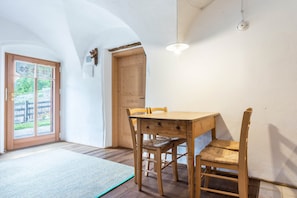 Ein Essbereich mit Holztisch und Stühlen, einer Fußmatte auf dem Boden, einer Holztür und einer Lampe.