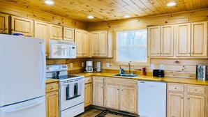 Une cuisine avec des meubles de rangement en bois, un réfrigérateur, un four à micro-ondes, une cuisinière et un évier.
