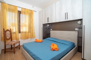 Una camera da letto con un letto, una sedia, una scrivania e un armadio.