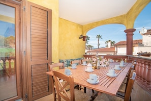 A dining area with a wooden table set for four, chairs, and a view of the surrounding landscape.