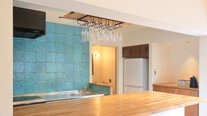 A modern kitchen with a wooden countertop, blue tiled backsplash, and a wine rack. - Villa Tono's Ishigakijima (Ishigaki)
