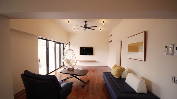 A modern living room with a sofa, armchair, and a table with a dreamcatcher. - Villa Tono's Ishigakijima (Ishigaki)