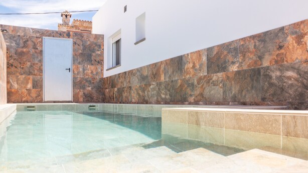 Una piscina con un muro de piedra y una puerta.