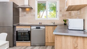 Una cocina moderna con un refrigerador de acero inoxidable, lavavajillas, horno empotrado y microondas.