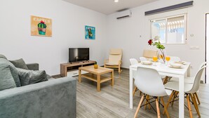 Una sala de estar moderna con un sofá, un televisor, una mesa de comedor con sillas y obras de arte en las paredes.