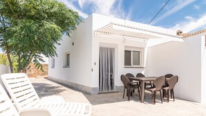 Un edificio blanco con un patio, que incluye una mesa y sillas, y un árbol.