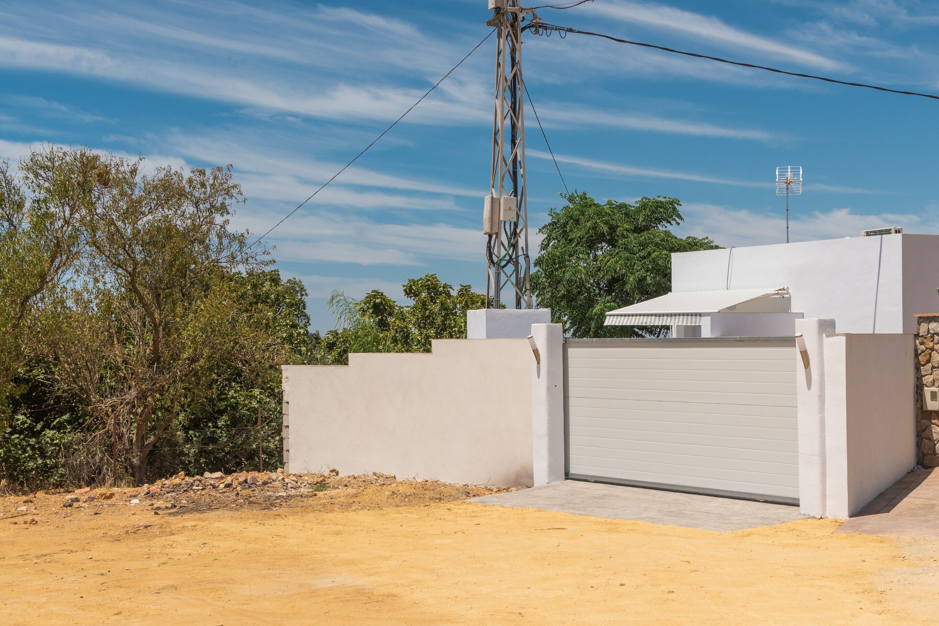 A modern building with a white exterior, a gated entrance, and a utility pole with wires.