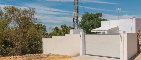 A modern building with a white exterior, a gated entrance, and a utility pole with wires.