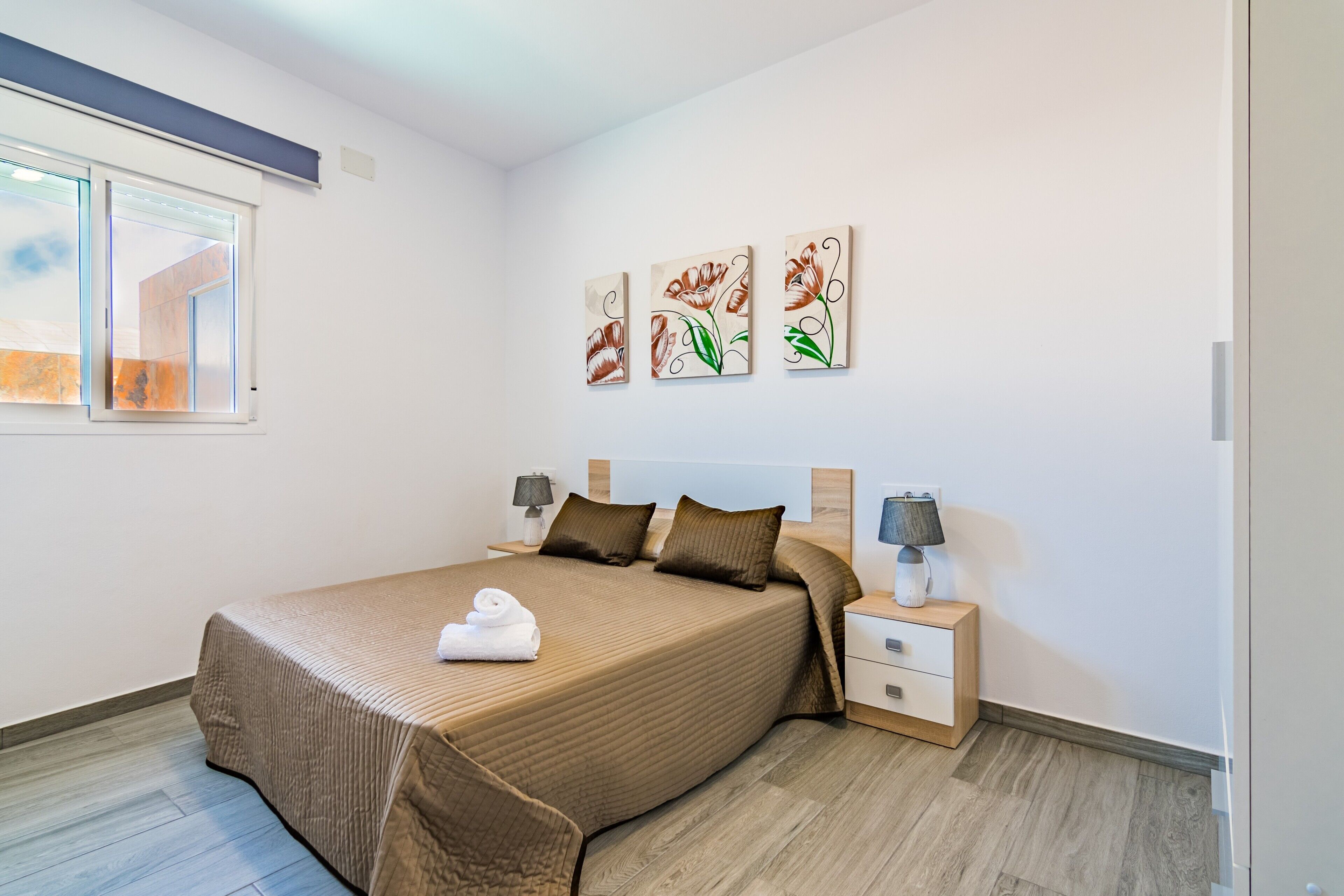 Een slaapkamer met een groot bed, nachtkastjes, een raam en wanddecoratie.