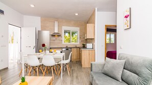 Una cocina moderna con comedor, un sofá gris y una mesa de madera con una piña.