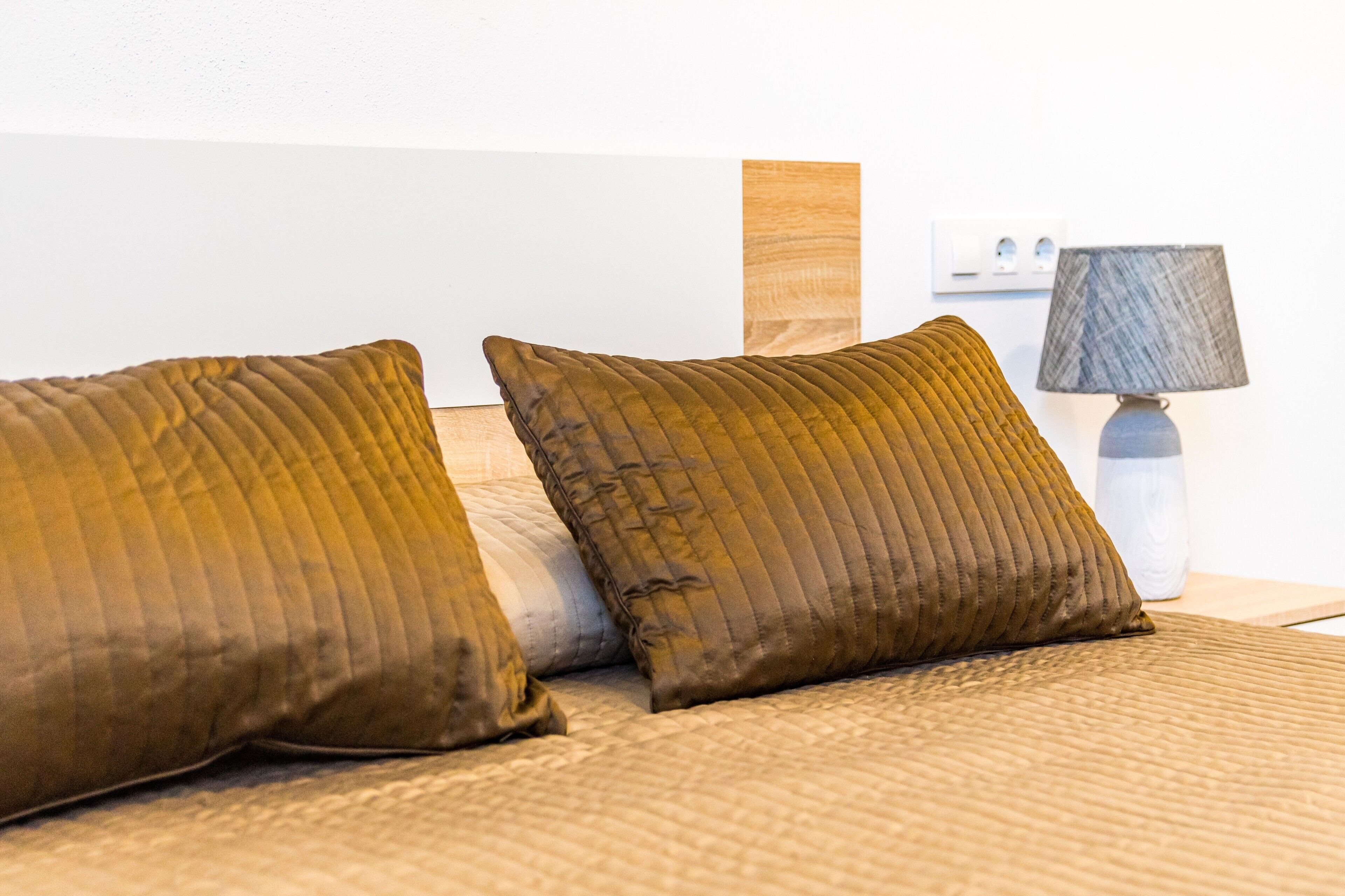 A bed with two pillows and a lamp on a bedside table.