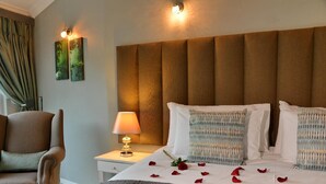A hotel room with a bed, a nightstand with a lamp, a chair, and a headboard. - The Shore House (Hartbeespoort)