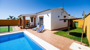 A swimming pool with lounge chairs, a covered patio, and a small house with a thatched roof. - Rustic Home Close to Beach with Pool, Terrace, Garden & Wi-Fi; Pets Allowed, Parking Available (Conil de la Frontera)