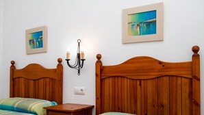 A bedroom with two wooden beds, a nightstand, a wall-mounted lamp, and two framed pictures. - Rustic Home Close to Beach with Pool, Terrace, Garden & Wi-Fi; Pets Allowed, Parking Available (Conil de la Frontera)