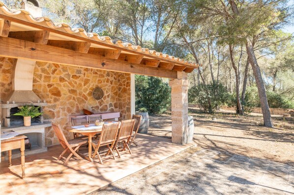 An outdoor patio with stone walls, wooden furniture, and a pergola.