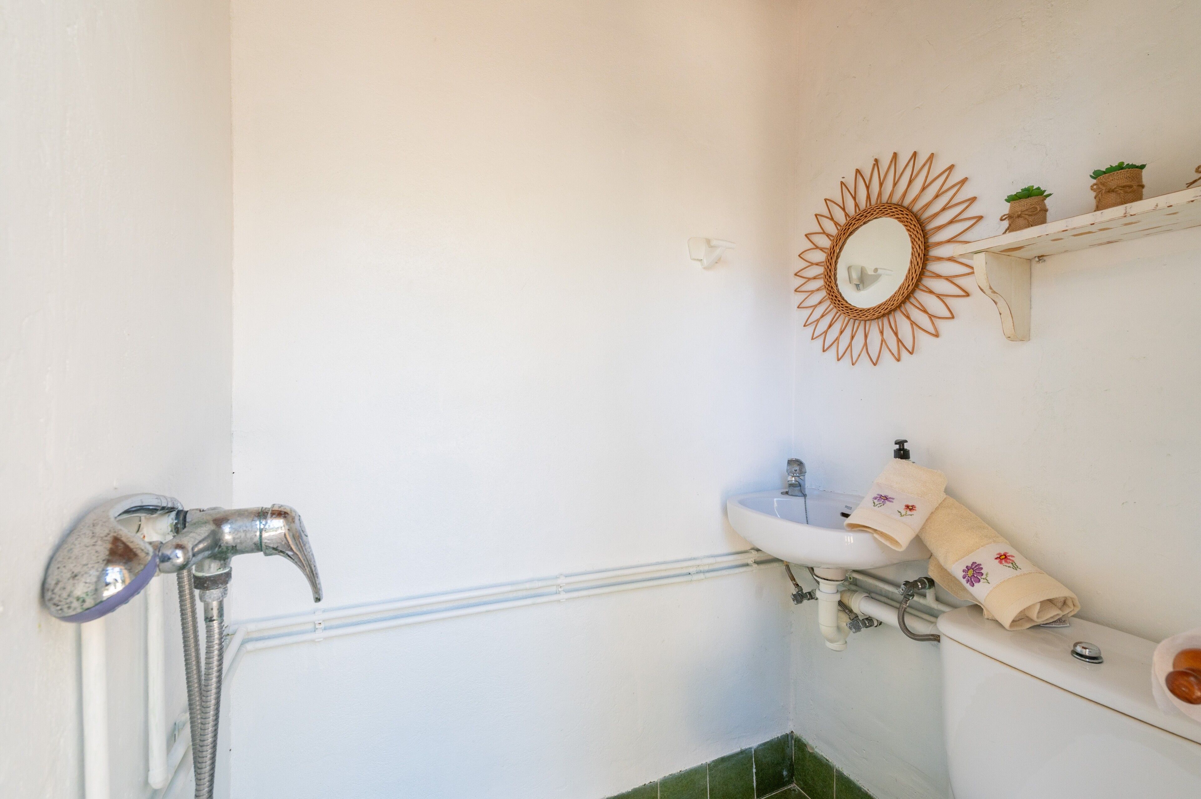 A bathroom with a shower, sink, toilet, and a decorative mirror.