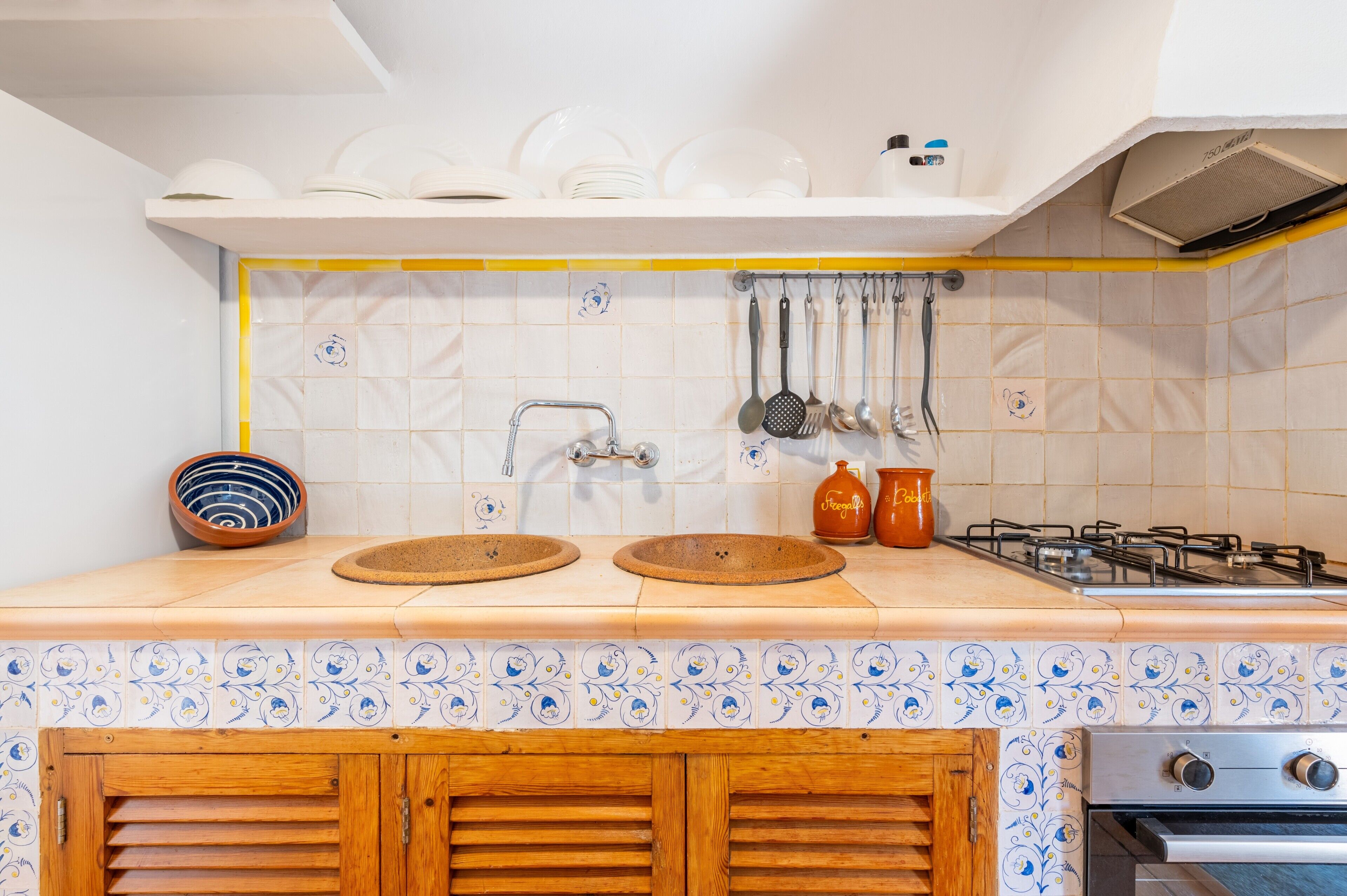 Een keuken met een dubbele spoelbak, een kookplaat en een kastje eronder.