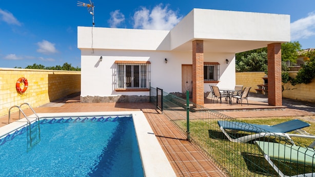 Una casa moderna con piscina, mobili da esterno e un cielo azzurro.