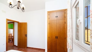 Una camera da letto con un letto, un armadio, un lampadario e una finestra con tende.