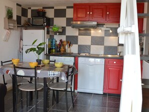Uma cozinha compacta com painel decorativo xadrez, micro-ondas, fogão e lava-louças.