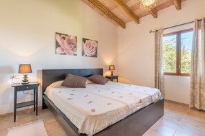 Une chambre à coucher avec un lit, deux tables de chevet avec des lampes, une tête de lit et une fenêtre avec des rideaux.