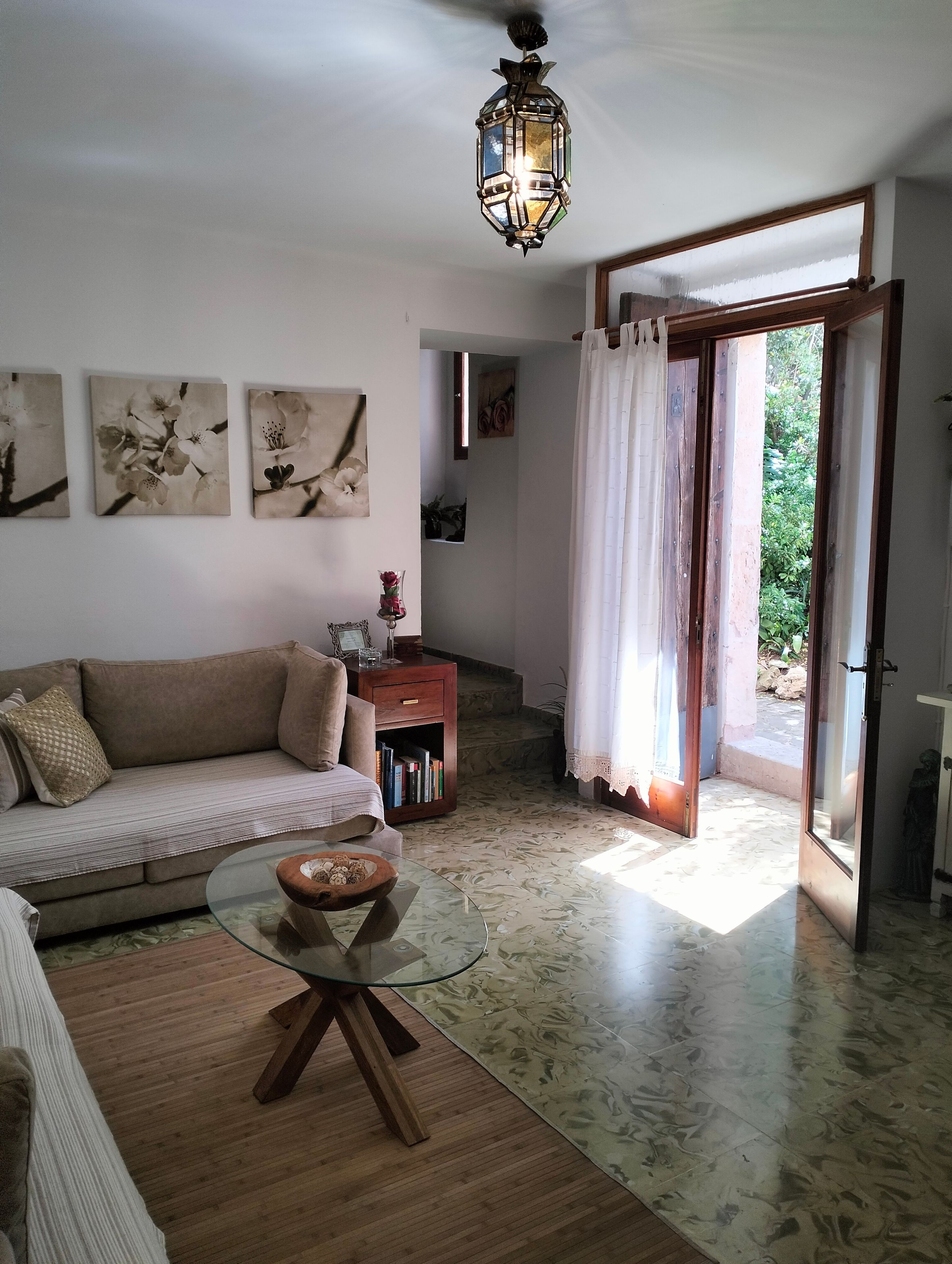 Un soggiorno con un divano, un tavolino in vetro e un lampadario.