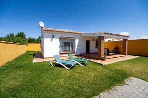 Una casa con un patio, dos sillones de descanso, una antena parabólica y un pequeño espacio de estar al aire libre.