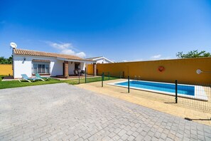 Una casa con piscina, un patio con sillones de descanso y una antena parabólica.