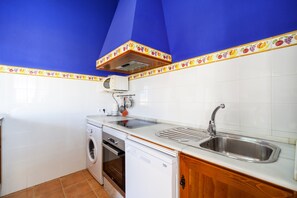 Una cocina equipada con lavadora, horno, lavavajillas y pileta.