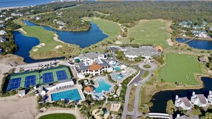 Ein Luftbild eines Golfresorts mit mehreren Seen, einem Tennisplatz und einem Schwimmbadbereich.