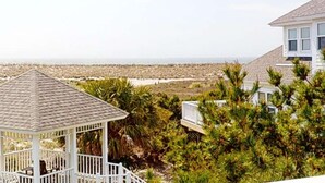 Ein Pavillon mit einem Ziegeldach, umgeben von üppiger Vegetation und Blick auf Strand und Meer.