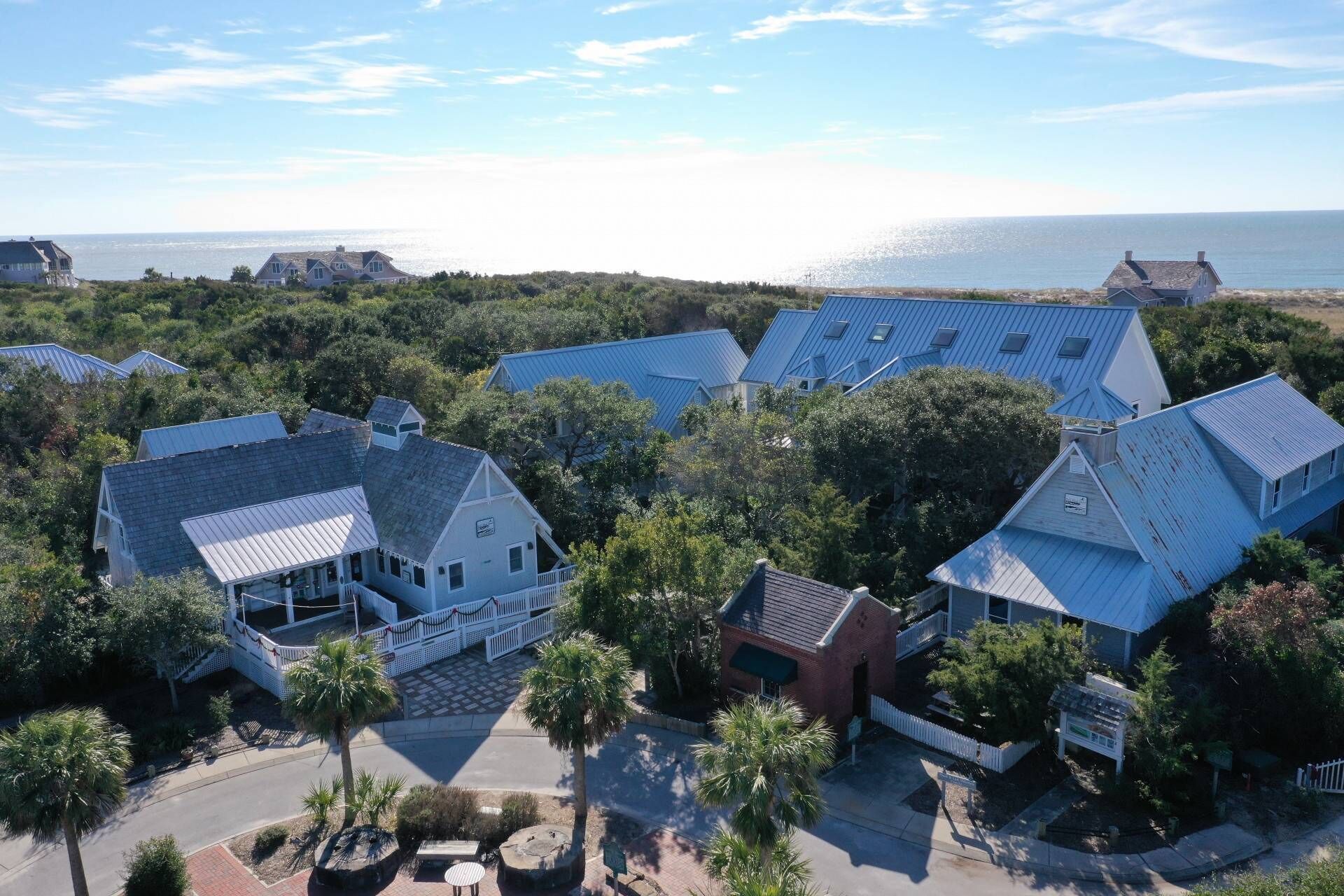 A coastal property with multiple buildings, a paved driveway, and a view of the sea.