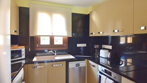 Una cocina compacta con microondas, estufa, lavabo y una ventana sobre la encimera.