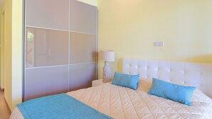 Un dormitorio con una cama grande, cabecera blanca y manta azul.