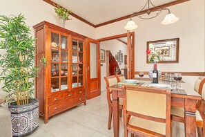 A dining area with a wooden cabinet, a dining table set for four, and a potted plant. - Air-Conditioned Apartment Close to Beaches with Rooftop Terrace (Nerja)