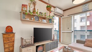 Una sala de estar con televisor de pantalla plana, mueble de madera, sofá y una mesita de centro.
