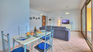 Un soggiorno moderno con zona pranzo, divano grigio e televisore.