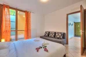 Une chambre d’hôtel avec un lit, un canapé, une porte-fenêtre coulissante et une vue sur un balcon.